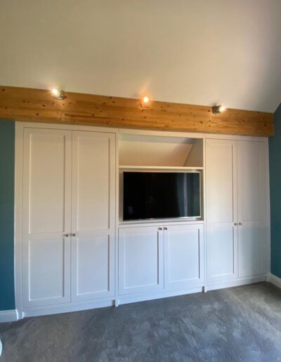 Shaker style bespoke wardrobe fitted around an existing wood beam, oak interiors finished ice white paint & we installed their TV