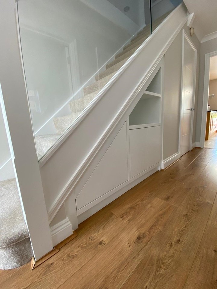 Custom-made under-stairs storage system designed to house their AC units, Finsauk oak internals, push touch doors, finished white ice paint.
