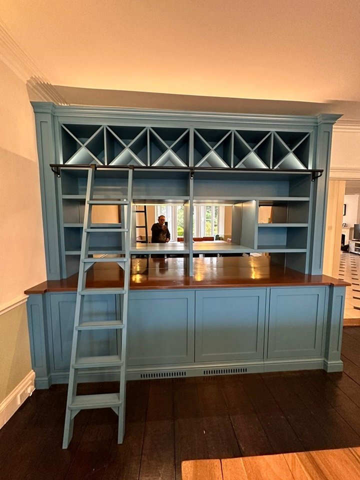 Custom-made bar unit with copper top & copper effect mirrors, oak internals, remote LED lights, moveable ladder, push touch doors, and housing hinges, finished in Little Greene Paint CO air force blue