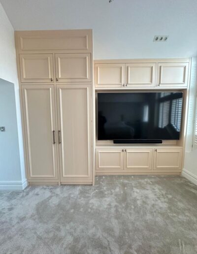 Detailed shaker-style wardrobe with an integrated TV unit, ample storage plus a concealed walkway leading to a stunning dressing roo