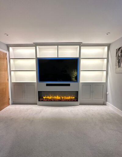 Bespoke media wall with Shaker-style cupboards & open shelving plus an inset electric fireplace, finished in French Grey Mid by Little Greene