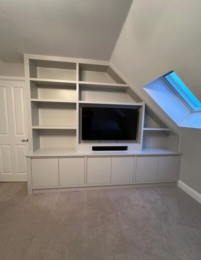Bespoke fitted media wall with a sleek, handleless finish with integrated soundbar & light switch finished in French Grey Mid by Little Greene.