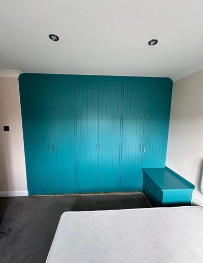 Custom-made 6-door Tongue & Groove style wardrobe with oak interiors and various storage options including hanging rails plus matching chest of drawers, bedside tables and cupboard all finished in Farrow & Ball Vardo