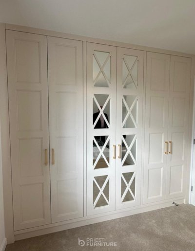 Custom-made 4-panel Shaker-Style wardrobes with mirrored fret doors, a combination of hanging rails & shelves, built-in chest of drawers with tie storage & LED lights