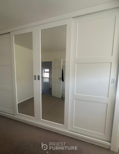 Custom-made sliding door wardrobes with chest of drawers, hanging rail, shelves and space for their safe